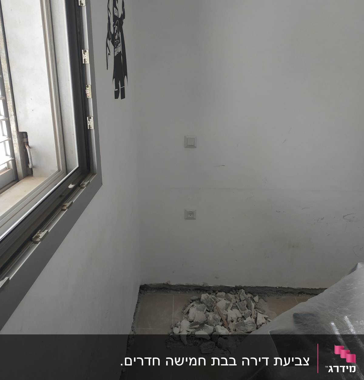 קיר לבן עם מדבקת דמות, ערימת פסולת על הרצפה